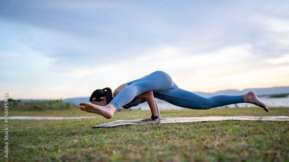 Fototapeta premium A woman doing yoga on a grassy field