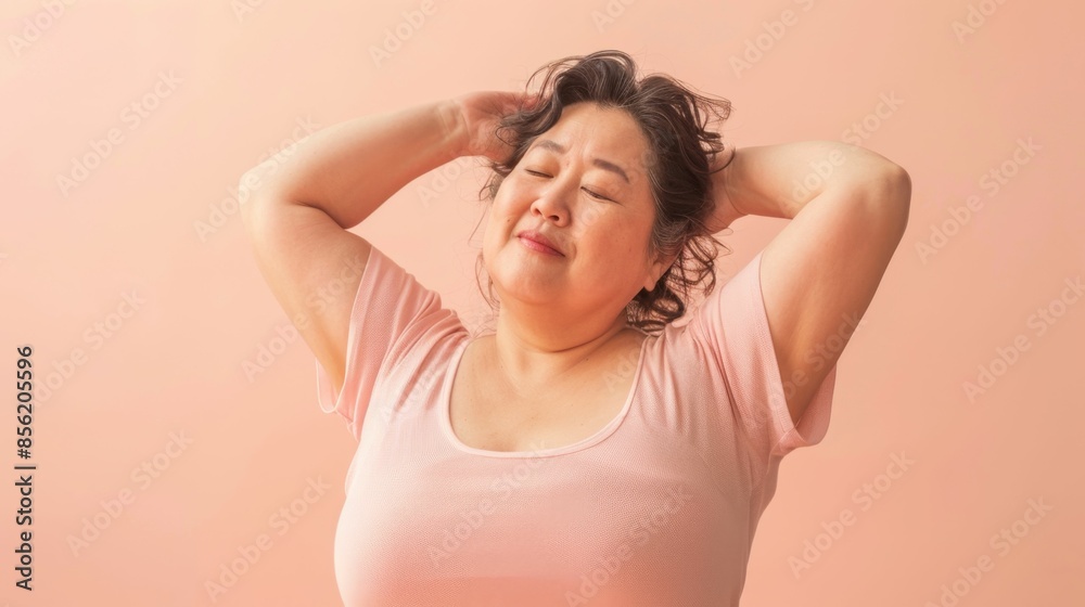 Woman in pink shirt with eyes closed smiling and hands on her head against a soft pink background. Woman in pink shirt with eyes closed smiling and hands on her head against a soft pink background.
