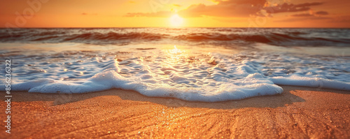 A serene beach sunset background with warm orange and pink hues, gentle waves, and textured sand. The peaceful, picturesque view creates a relaxing, tranquil scene.