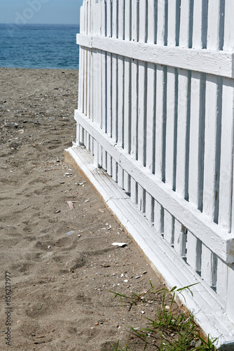 White painted fence in the sand on the beach