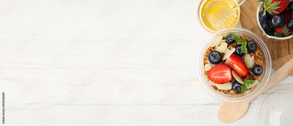 Tasty dessert with granola and berries on white wooden table, flat lay. Banner design with space for text Tasty dessert with granola and berries on white wooden table, flat lay. Banner design with space for text