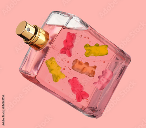 Perfume bottle with sweet gummy bears inside on coral color background, creative collage