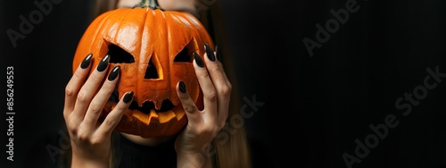 halloween autumn celebration party holiday background concept greeting card banner  - Close up of pretty woman holding a carved pumpkin in her hands, isolated on black background.