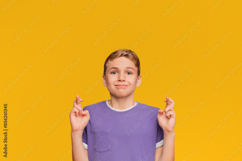 Teenager crossing fingers wishing, praying for miracle, orange studio background, panorama Teenager crossing fingers wishing, praying for miracle, orange studio background, panorama
