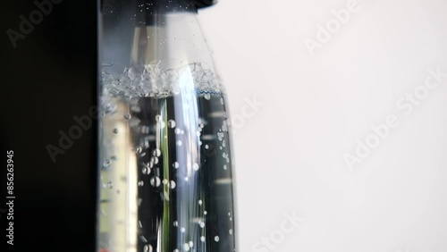 A glass bottle fills with sparkling soda, showcasing the process of carbonation photo