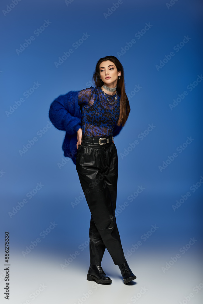 A young woman stands in a stylish pose against a blue background. A young woman stands in a stylish pose against a blue background.