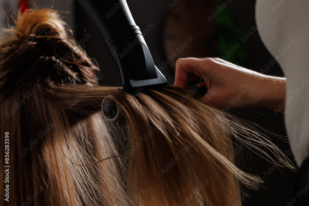 Fototapeta premium hairdresser drying hair with hair dryer and comb in beauty salon, drying hair close-up