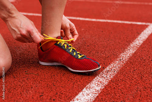 A runner bending down to tie their sneakers on the racing track before the competition starts photo