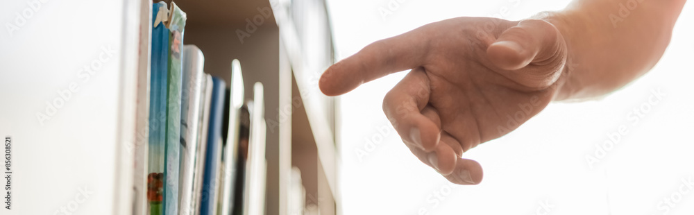 A hand reaches for a book in a bookcase. A hand reaches for a book in a bookcase.
