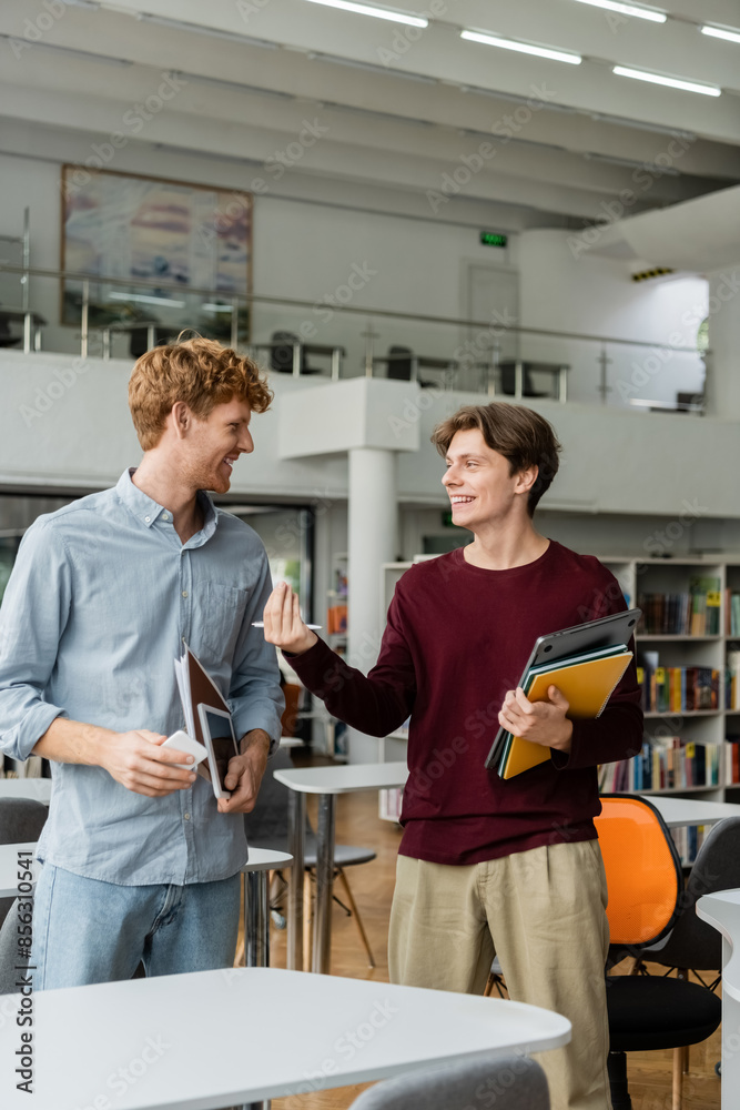 Obraz premium Two young men engrossed in conversation at a library.