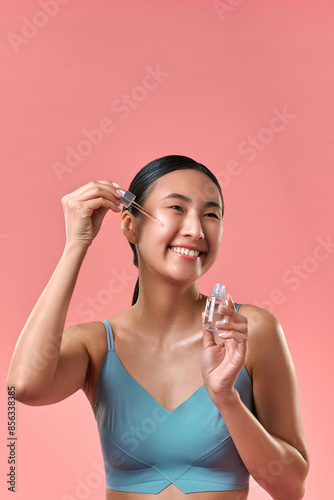  New skincare product. Beautiful female with radiant smile testing recently released cosmetology fluid for increasing collagen creation. Sensual lady trying new method of aging signs prevention.
