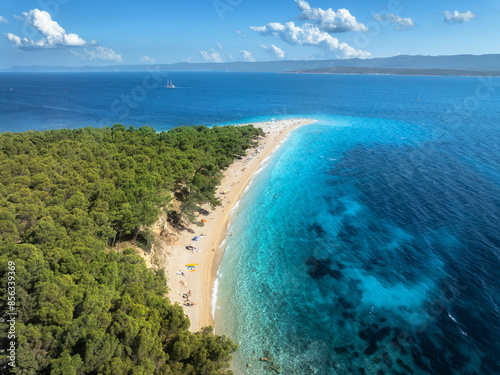 Aerial view of blue sea and Zlatni Rat, Brac island, Croatia in summer. Top drone view of adriatic sea, sandbank, white sandy beach, green trees, clear azure water at sunset. Tropical landscape photo