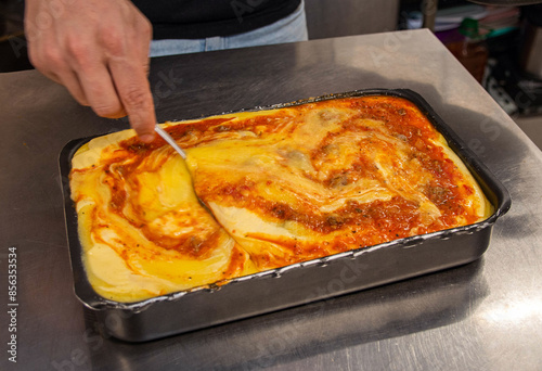 Cooked corn meal being prepared and stuffed with bolognese sauce in a restaurant kitchen. photo