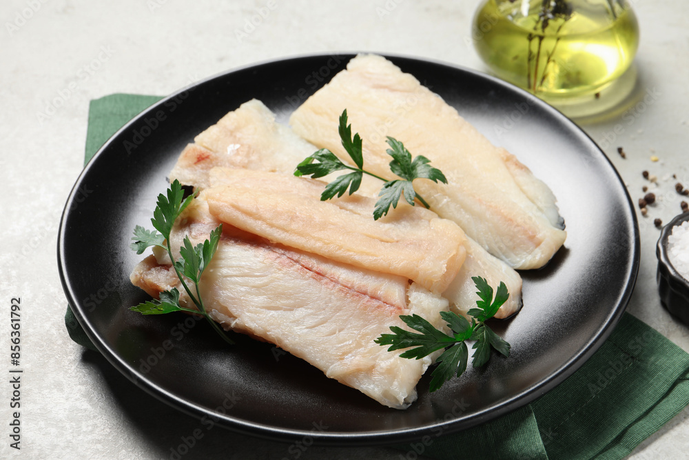 Plate with raw cod fish and parsley on light table, closeup Plate with raw cod fish and parsley on light table, closeup