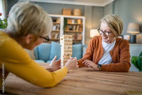 two senior women friends or sisters play leisure board game at home