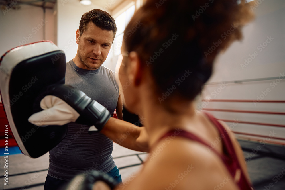 Boxing trainer with female fighter during sports training in health club.. Boxing trainer with female fighter during sports training in health club..
