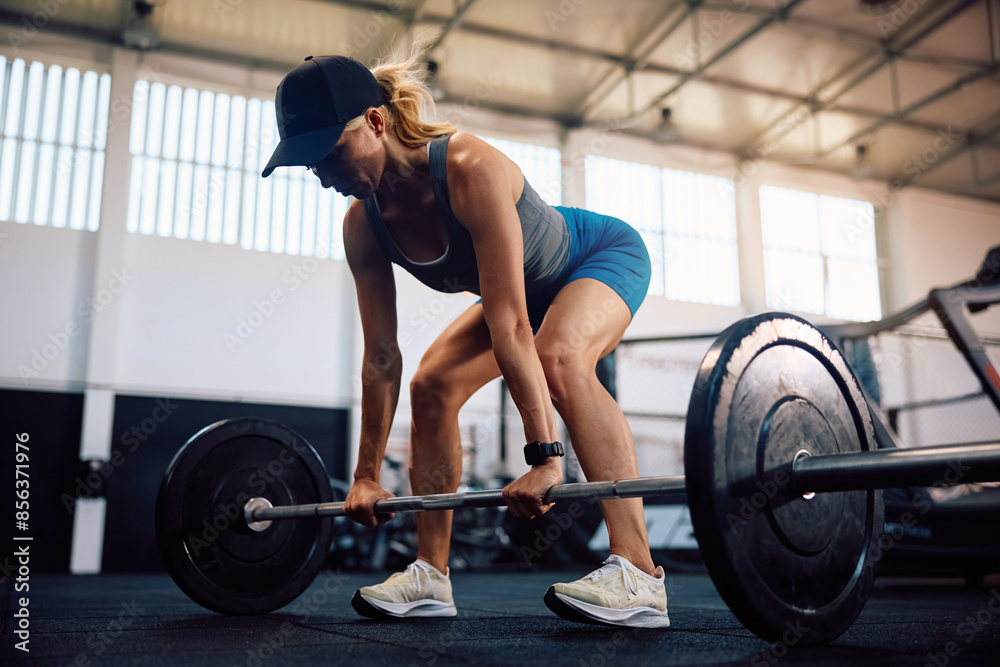 Muscular build woman lifting barbell doing weight training in health club. Muscular build woman lifting barbell doing weight training in health club.