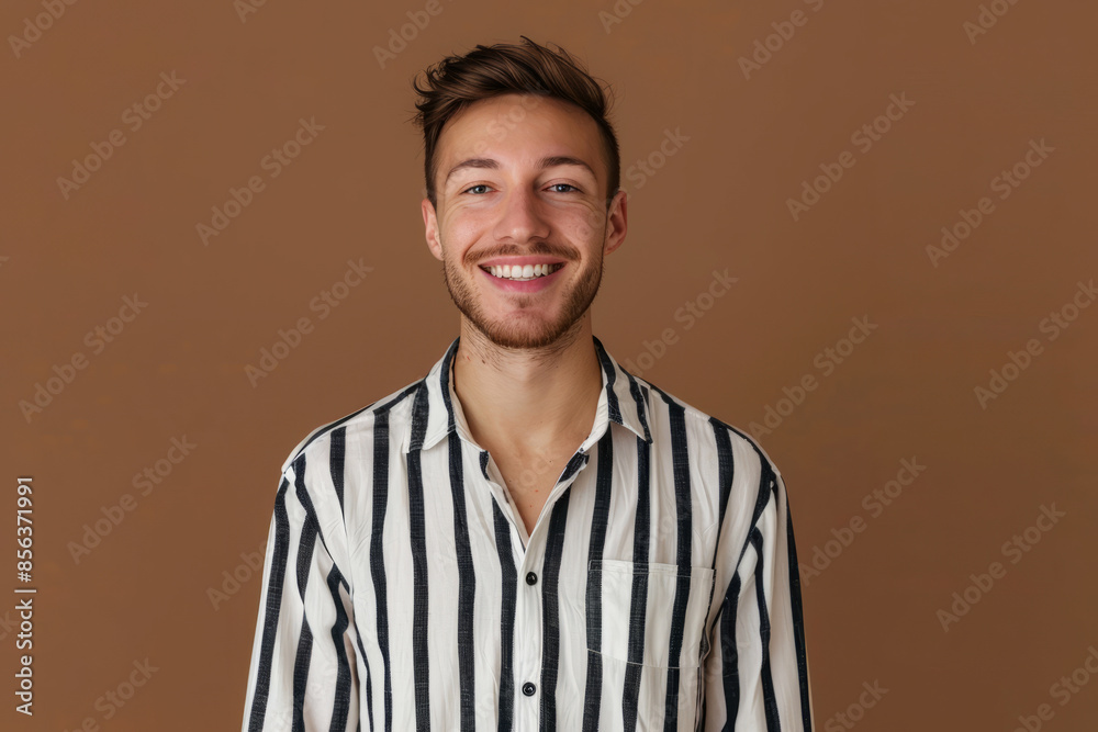 Obraz premium Portrait of nice young man smiling, wearing striped t-shirt isolated on meringue empty background 
