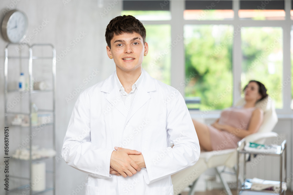 Obraz premium Portrait of young male doctor wearing uniform standing in treatment room at clinic