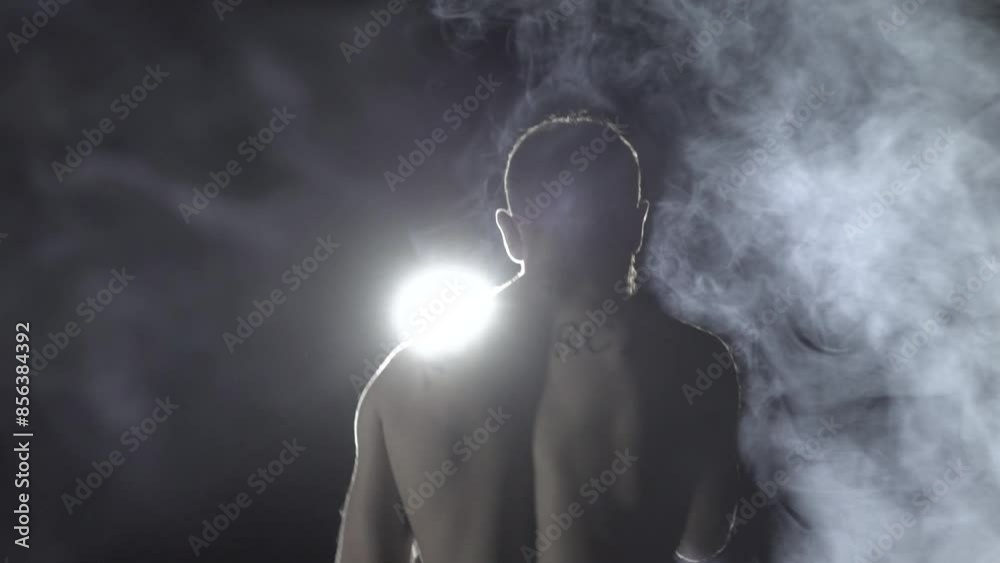 Boxer does warm-up on background of spotlight and smoke