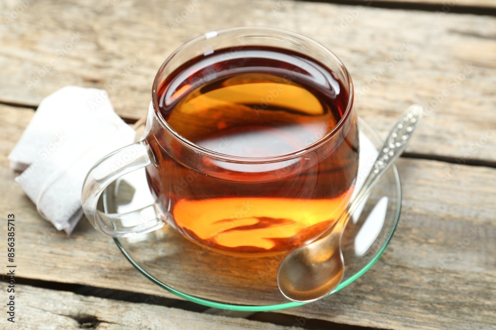Aromatic tea in glass cup, spoon and teabags on wooden table Aromatic tea in glass cup, spoon and teabags on wooden table