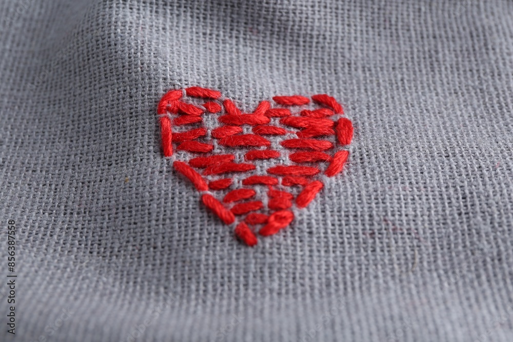 Fototapeta premium Embroidered red heart on gray cloth, above view