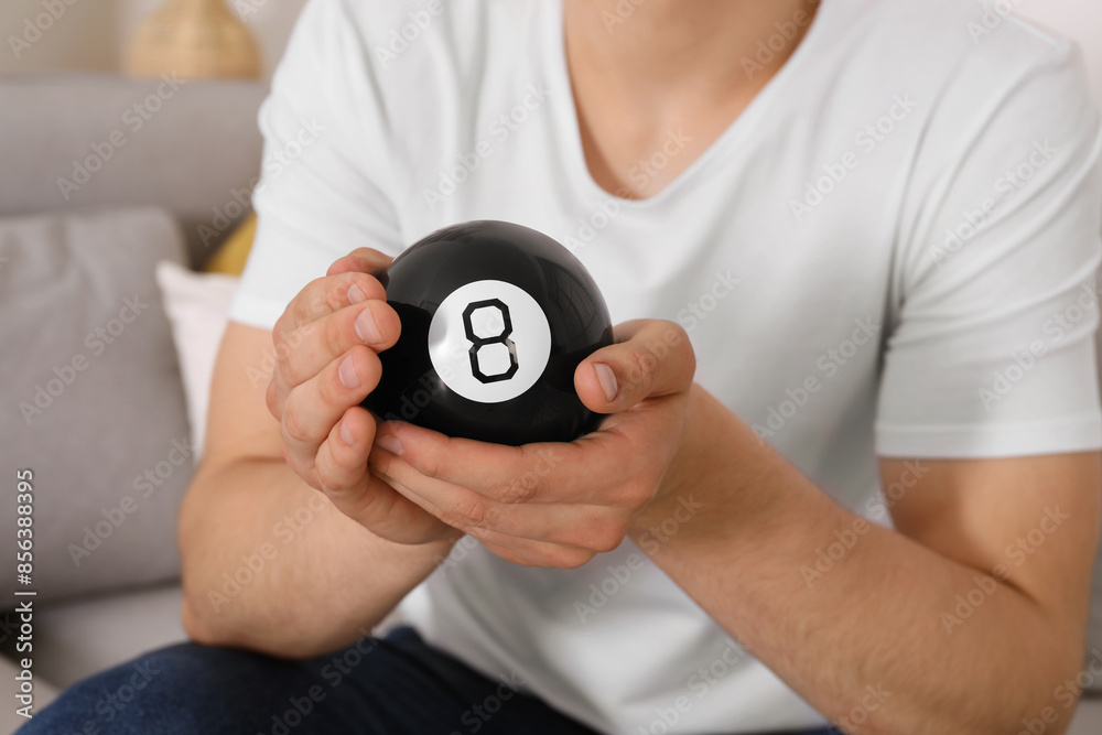 Man holding magic eight ball indoors, closeup Man holding magic eight ball indoors, closeup