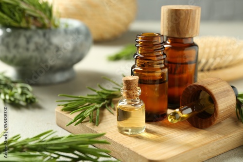 Photography Essential oils in bottles and rosemary on light gray table, closeup