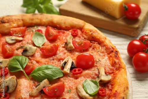 Delicious pizza with tomatoes, mushrooms and basil on wooden table, closeup