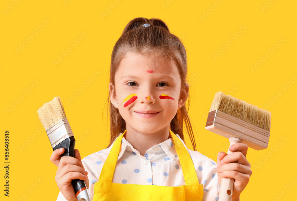 Cute little girl with face in paint and brushes on yellow background, closeup Cute little girl with face in paint and brushes on yellow background, closeup