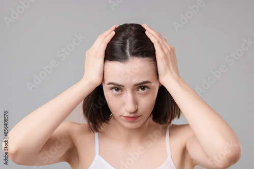Sad woman with hair loss problem on grey background