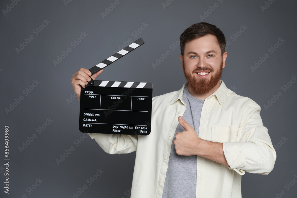 Making movie. Smiling man with clapperboard showing thumb up on grey background. Space for text Making movie. Smiling man with clapperboard showing thumb up on grey background. Space for text