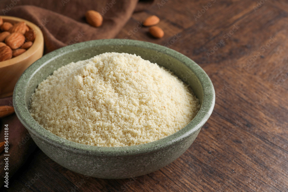 Fresh almond flour in bowl and nuts on wooden table, closeup. Space for text Fresh almond flour in bowl and nuts on wooden table, closeup. Space for text