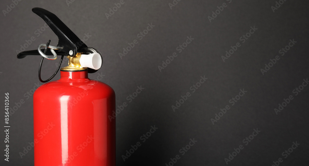One red fire extinguisher on dark gray background, space for text One red fire extinguisher on dark gray background, space for text