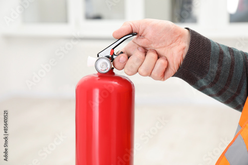 Man with one fire extinguisher indoors, closeup