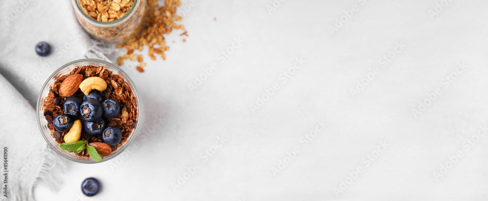 Tasty dessert with granola, nuts and blueberries on white table, flat lay. Banner design with space for text Tasty dessert with granola, nuts and blueberries on white table, flat lay. Banner design with space for text