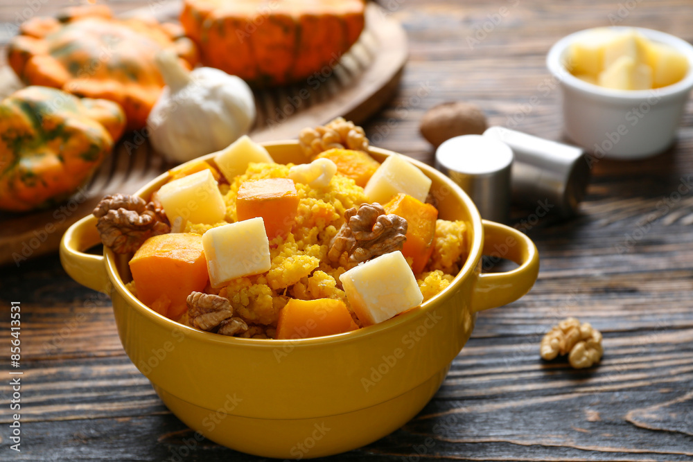 Pot of tasty millet porridge with pumpkin and cheese on wooden background Pot of tasty millet porridge with pumpkin and cheese on wooden background