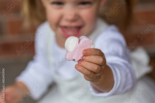 Little girl holding easter bunny shaped marshmallow photo