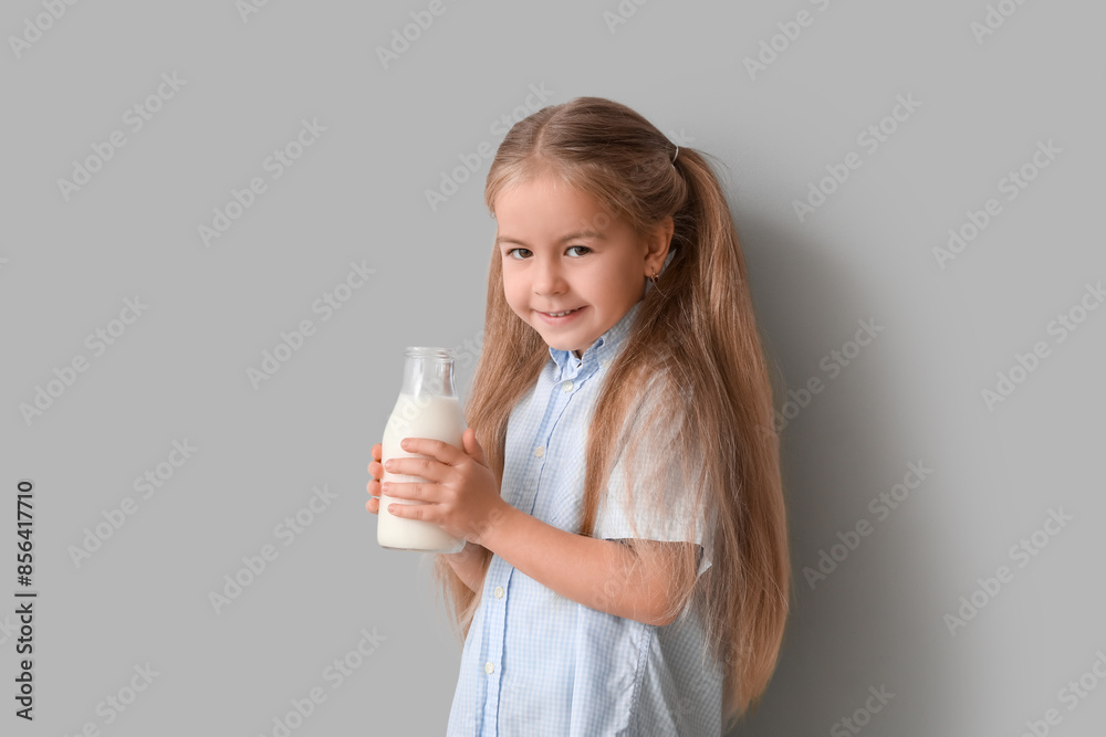 Cute little girl with bottle of tasty milk on grey background Cute little girl with bottle of tasty milk on grey background