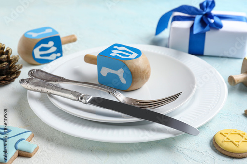 Festive table setting with Hanukkah decorations on light blue background, closeup photo