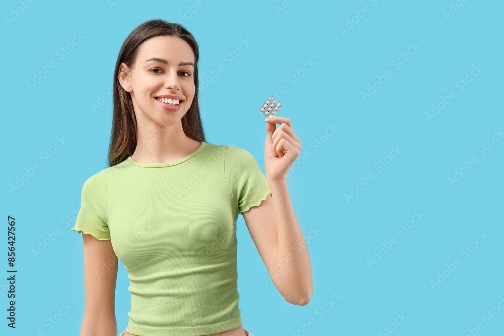 Beautiful young woman with birth control pills on blue background Beautiful young woman with birth control pills on blue background