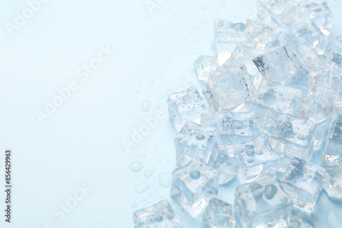 Crystal clear ice cubes on light blue background, flat lay. Space for text