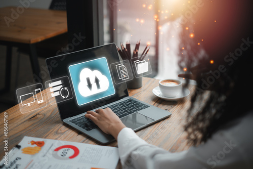 Valokuva A person working on a laptop with cloud backup icons, symbolizing data security and storage solutions in a contemporary office setting