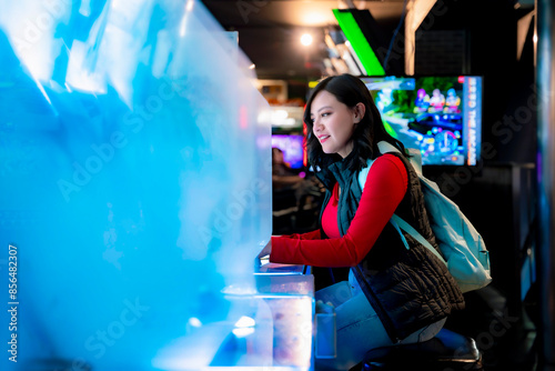 Canvas Print A young Latina woman smiling while playing arcade games in Akihabara, Tokyo, Japan, with glowing futuristic screens