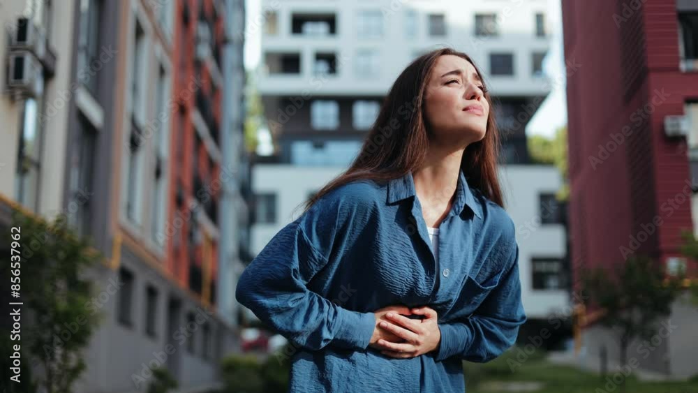 Young woman with strong stomach ache. Woman suffering from abdominal pain while standing outdoors. Young woman with strong stomach ache. Woman suffering from abdominal pain while standing outdoors.