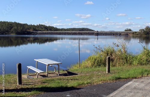 Picnic table next to Lake Monduran with a forest of trees in the distance in Queensland, Australia photo