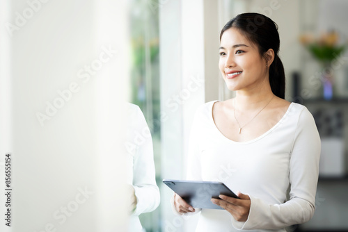 Smart caucasian woman in casual wear holding digital tablet standing at home. © NAMPIX