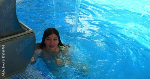 Pretty teenage girl having fun in an indoor swimming pool on vacation