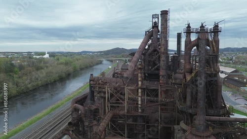 Abandoned blast furnaces in Bethlehem PA. Medium aerial shot pans from right to left of the end of a blast furnace. Railroad, river, and city are visible in the background.