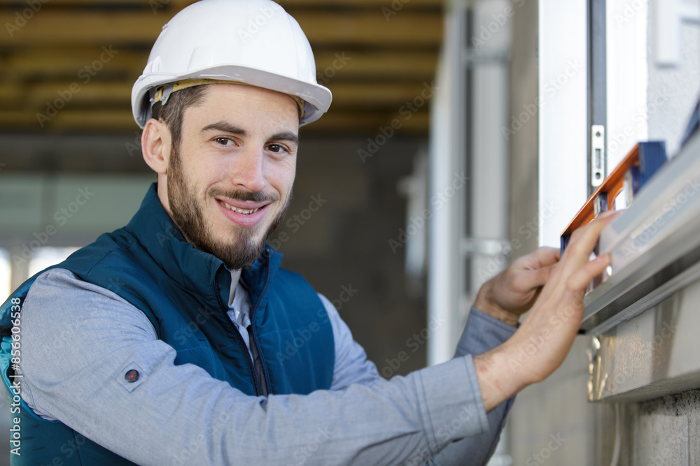 male builder using spirit level to check window male builder using spirit level to check window